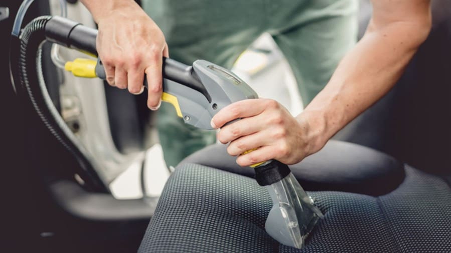 Fachgerechte Reinigung eines Autositzes mit professioneller Extraktionsmaschine im Innenraum eines Fahrzeugs